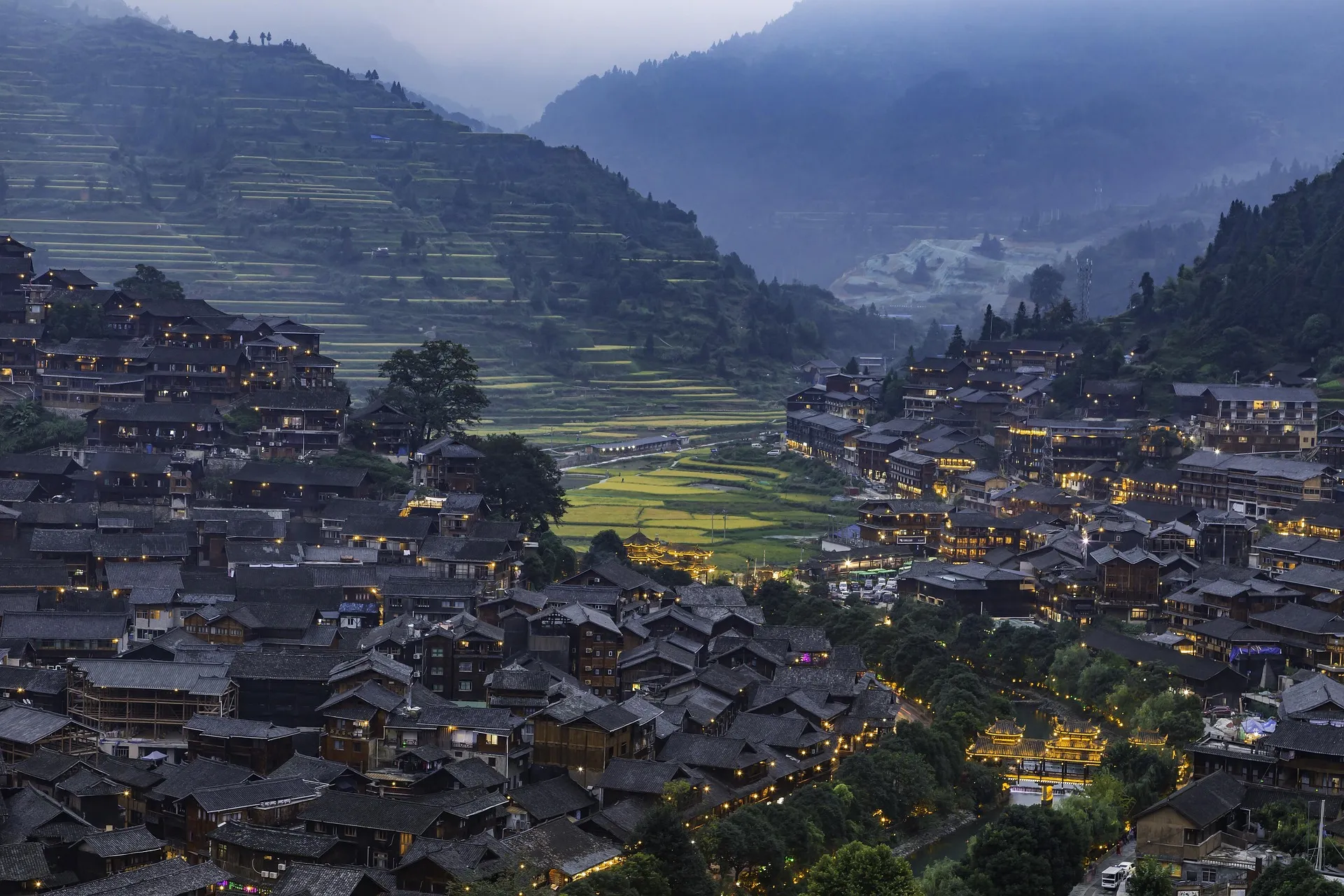 Bergdorf im Hochland von Guizhou in der Abenddämmerung, Nebel über den Terrassen